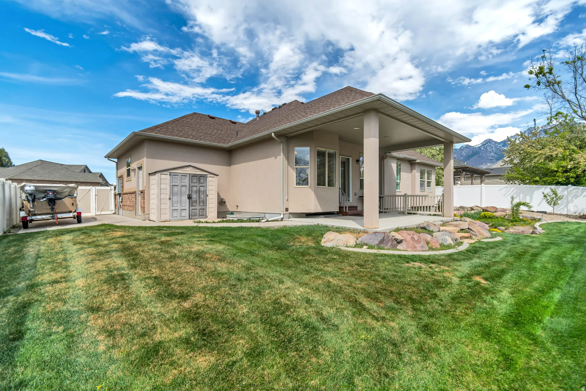 Rear view of property featuring a patio, stucco siding, a fenced backyard, and a storage shed