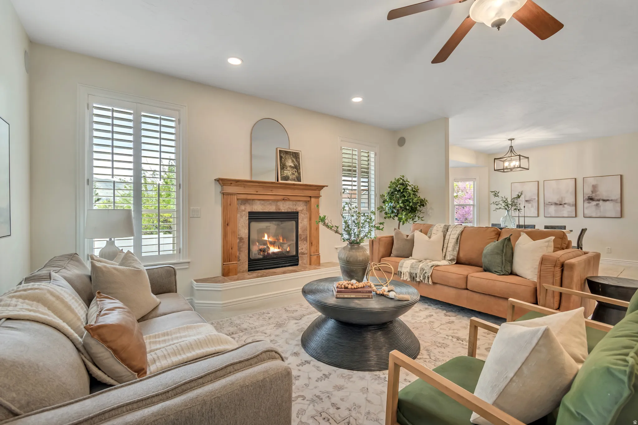 Living room with a ceiling fan, a premium fireplace, and suspended lighting