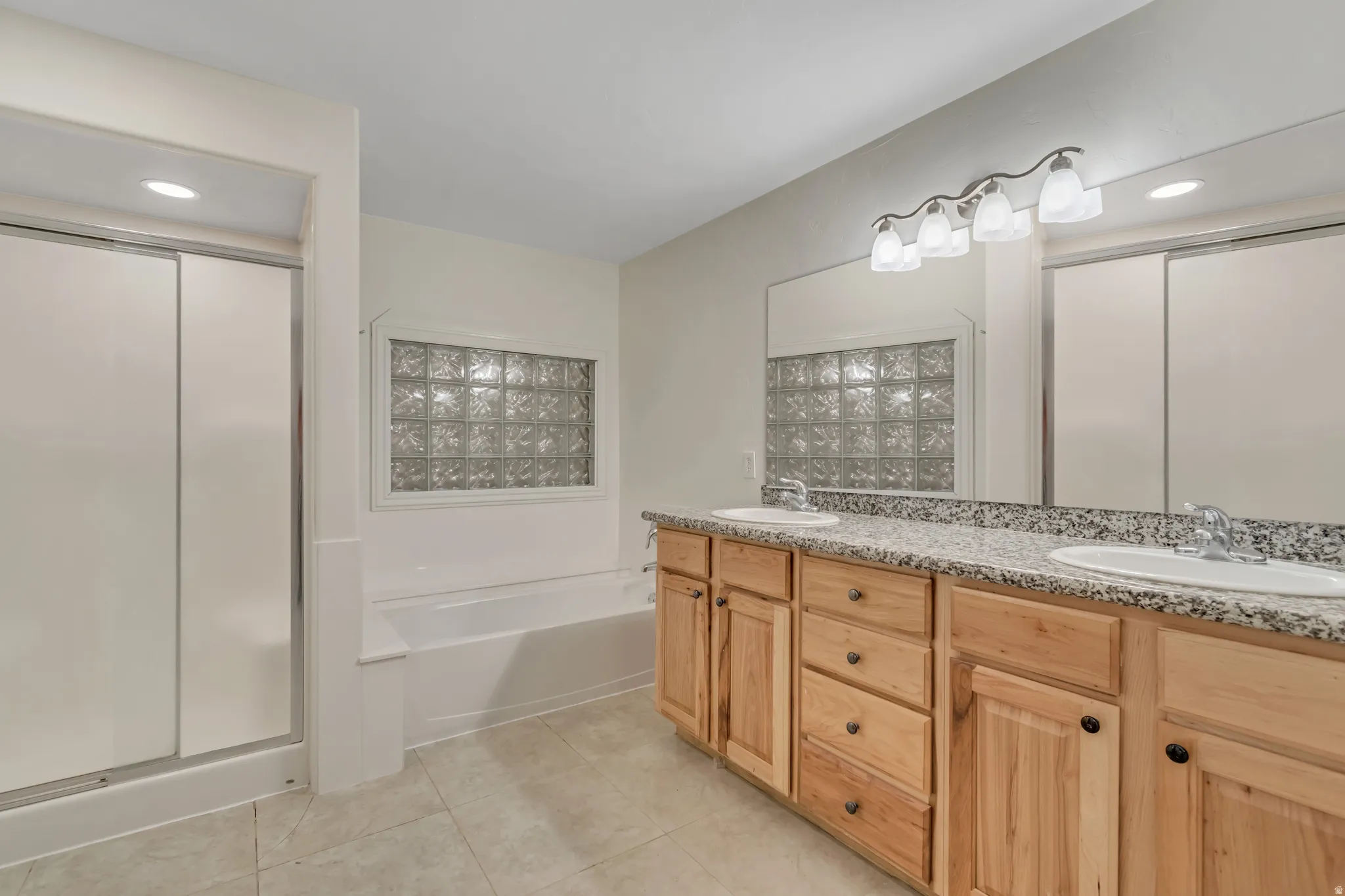 Full bathroom with recessed lighting, double vanity, a garden tub, light tile patterned floors, and a shower stall