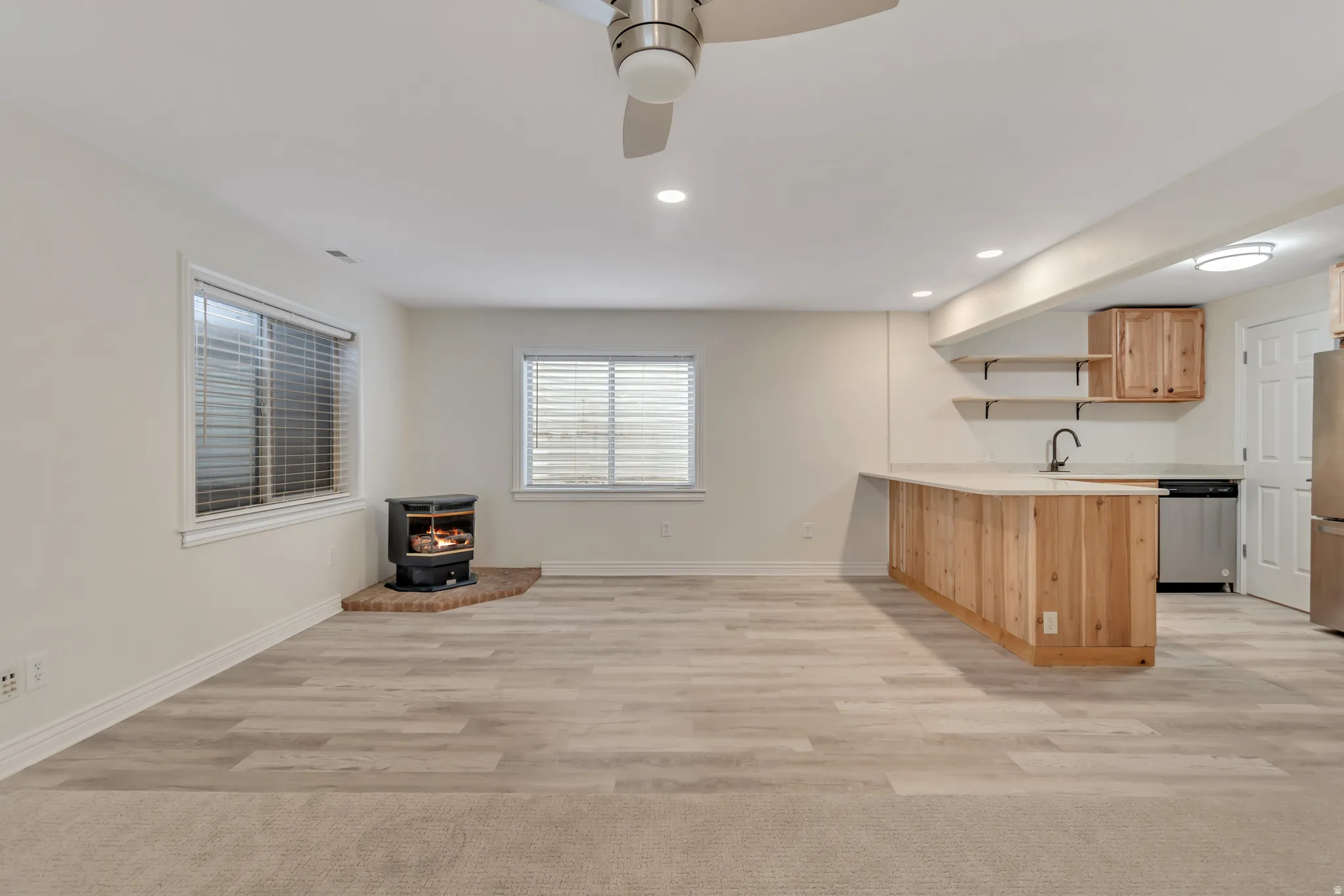 Kitchen featuring a peninsula, open shelves, light countertops, a wood stove, and recessed lighting