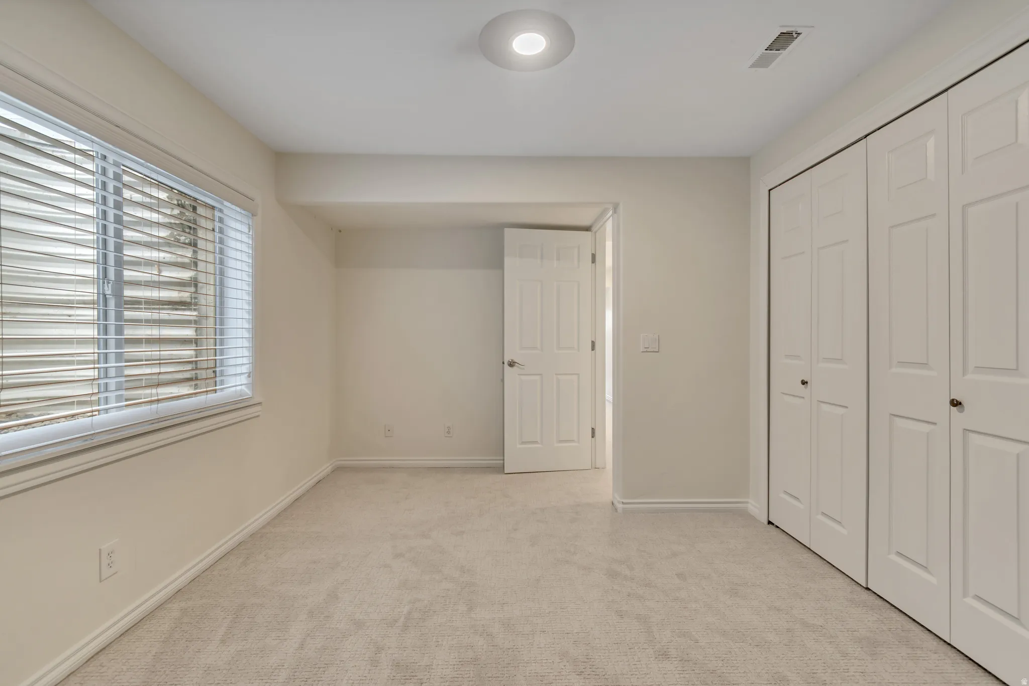 Unfurnished bedroom featuring light colored carpet and a closet