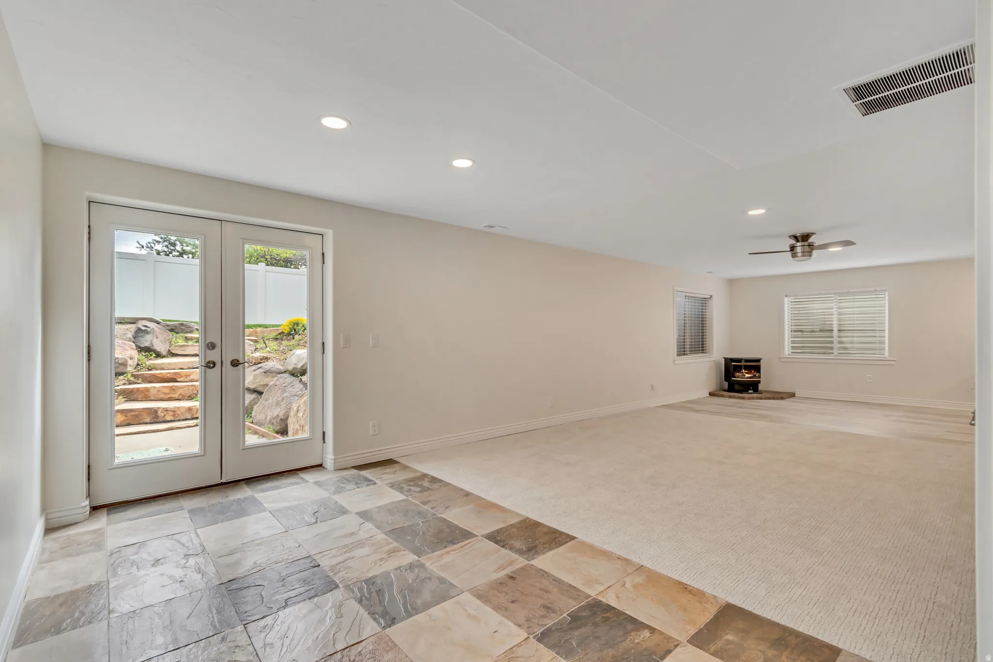 Unfurnished living room featuring french doors, light colored carpet, stone tile flooring, recessed lighting, and ceiling fan