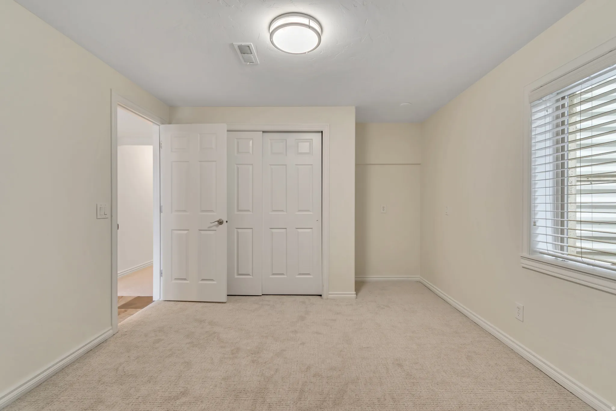 Unfurnished bedroom with light colored carpet and a closet