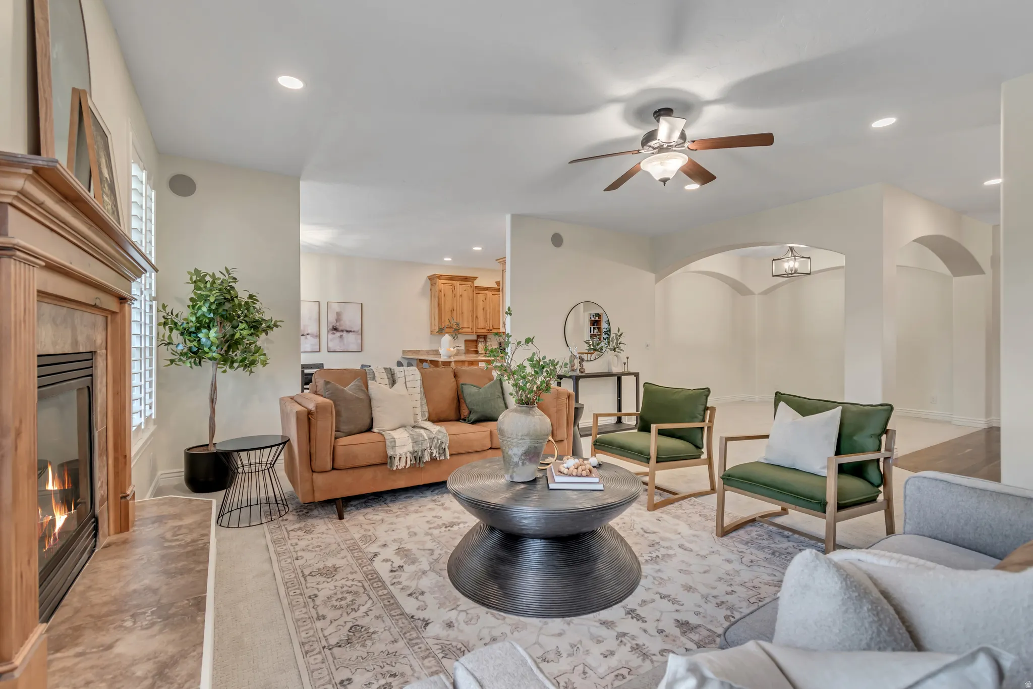 Living area featuring a tile fireplace, ceiling fan, recessed lighting, and arched walkways
