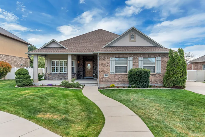 View of front of house with a porch, a shingled roof, stucco siding, and brick siding