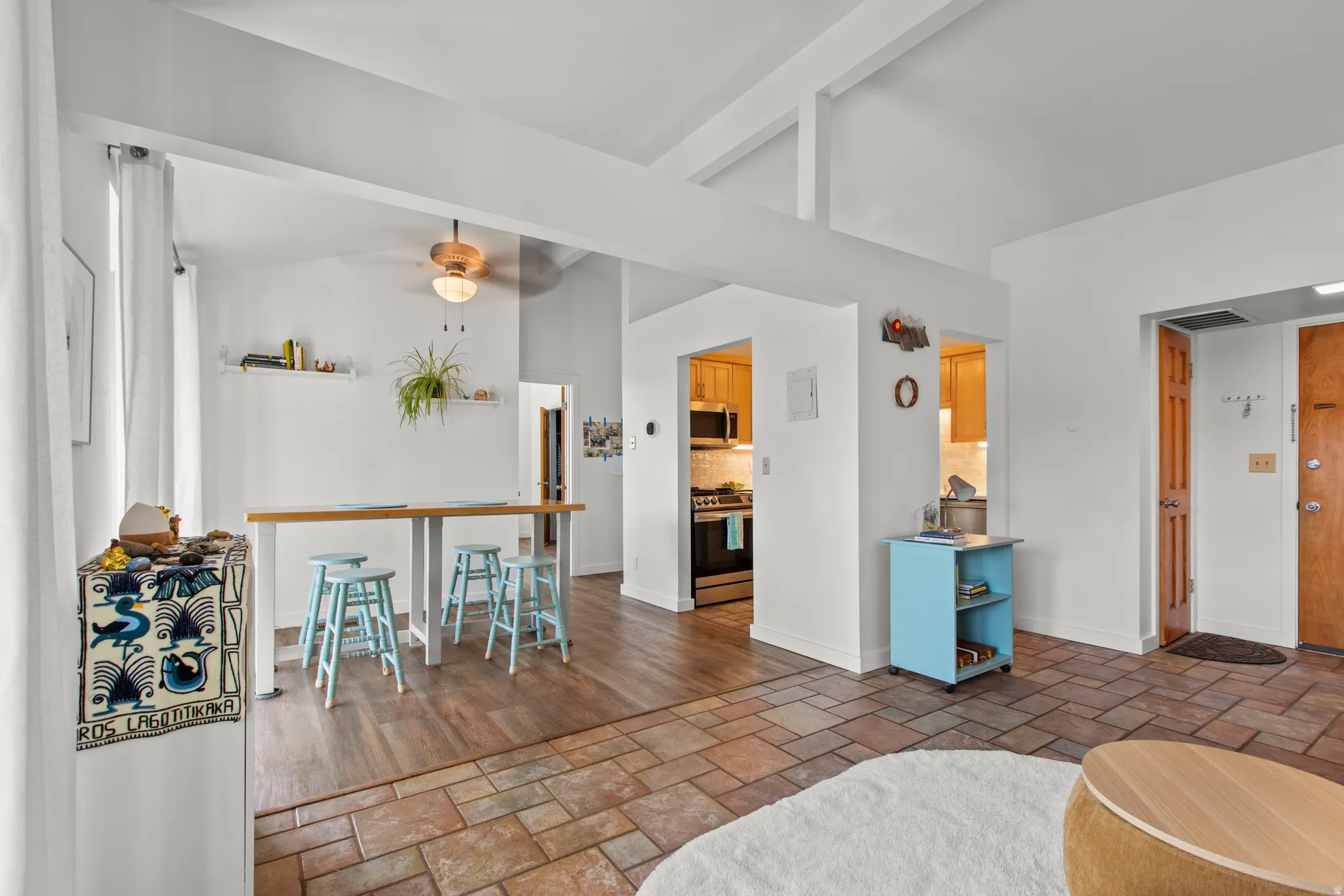 Living room with stone tile floors, ceiling fan, and lofted ceiling with beams