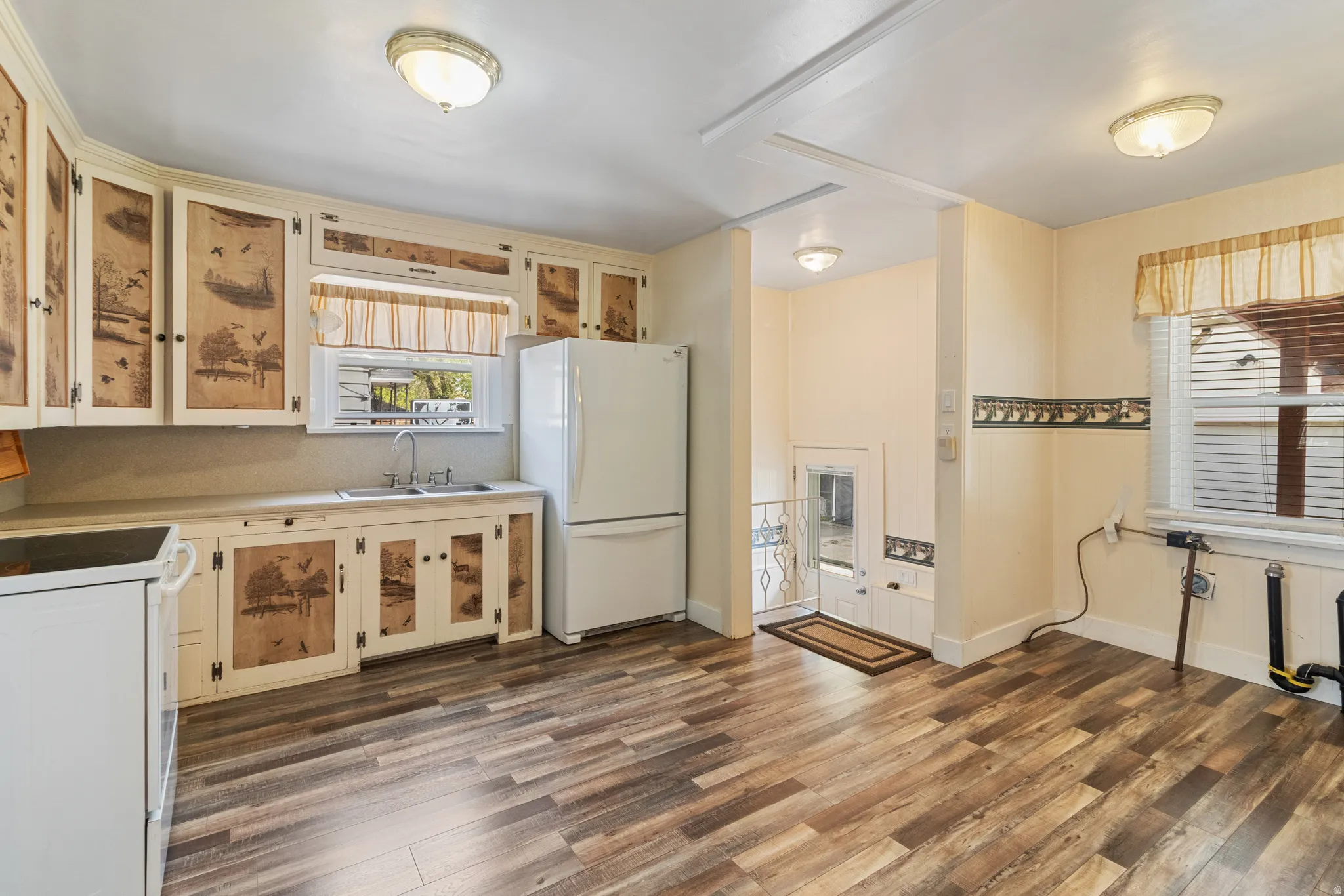 Kitchen with white appliances, dark wood-type flooring, light countertops, and glass insert cabinets
