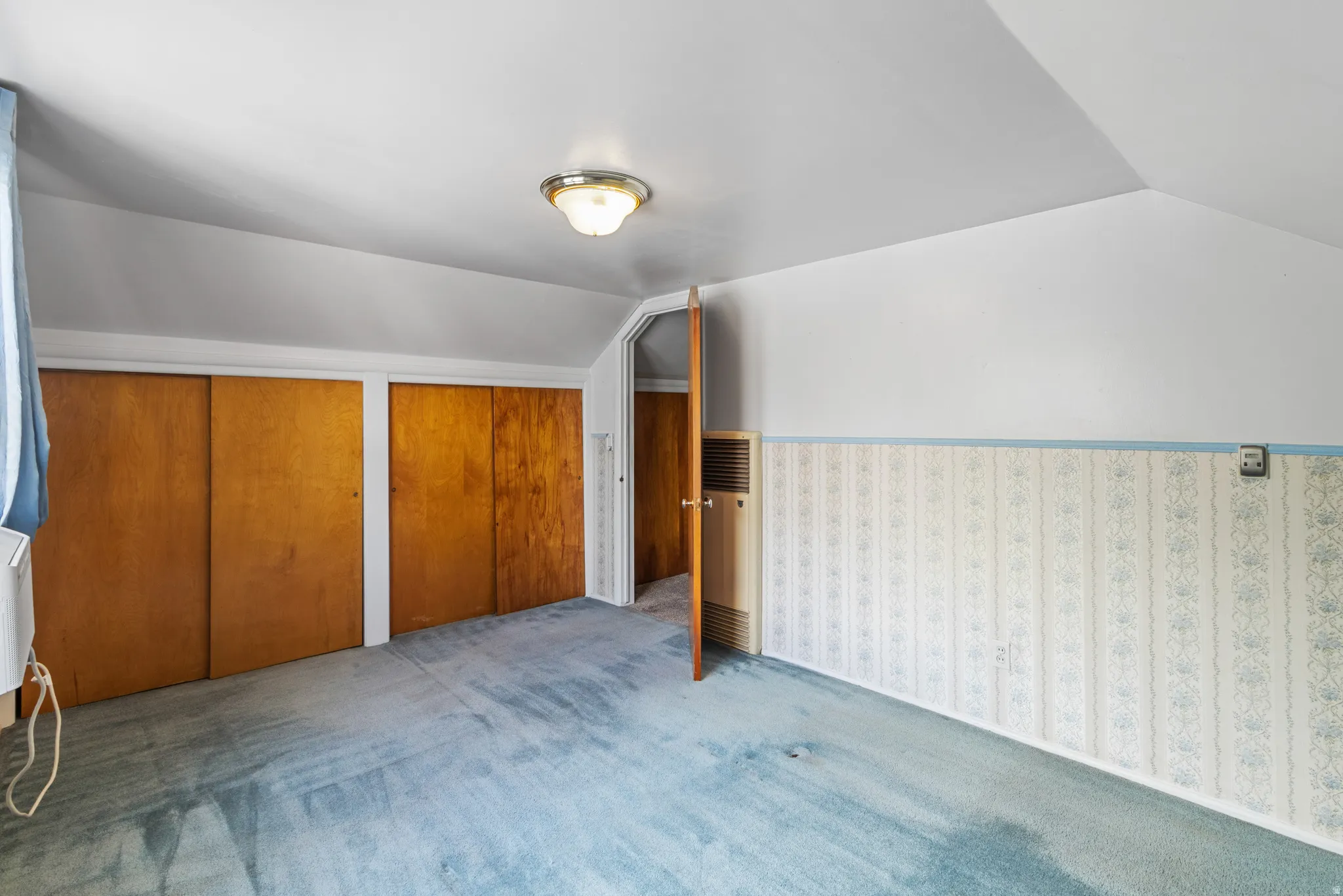 Additional living space featuring vaulted ceiling, a heating unit, a wainscoted wall, and carpet