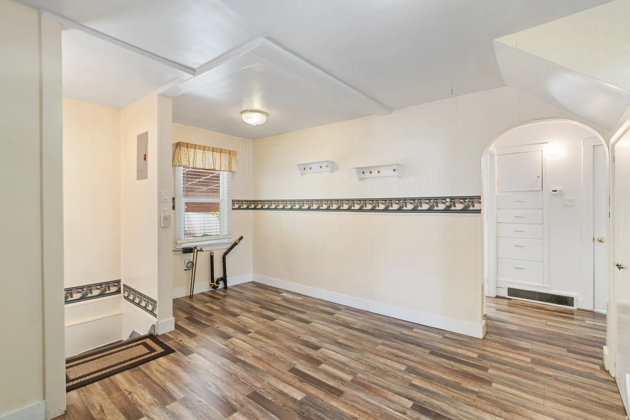 Unfurnished dining area with arched walkways and dark wood-type flooring