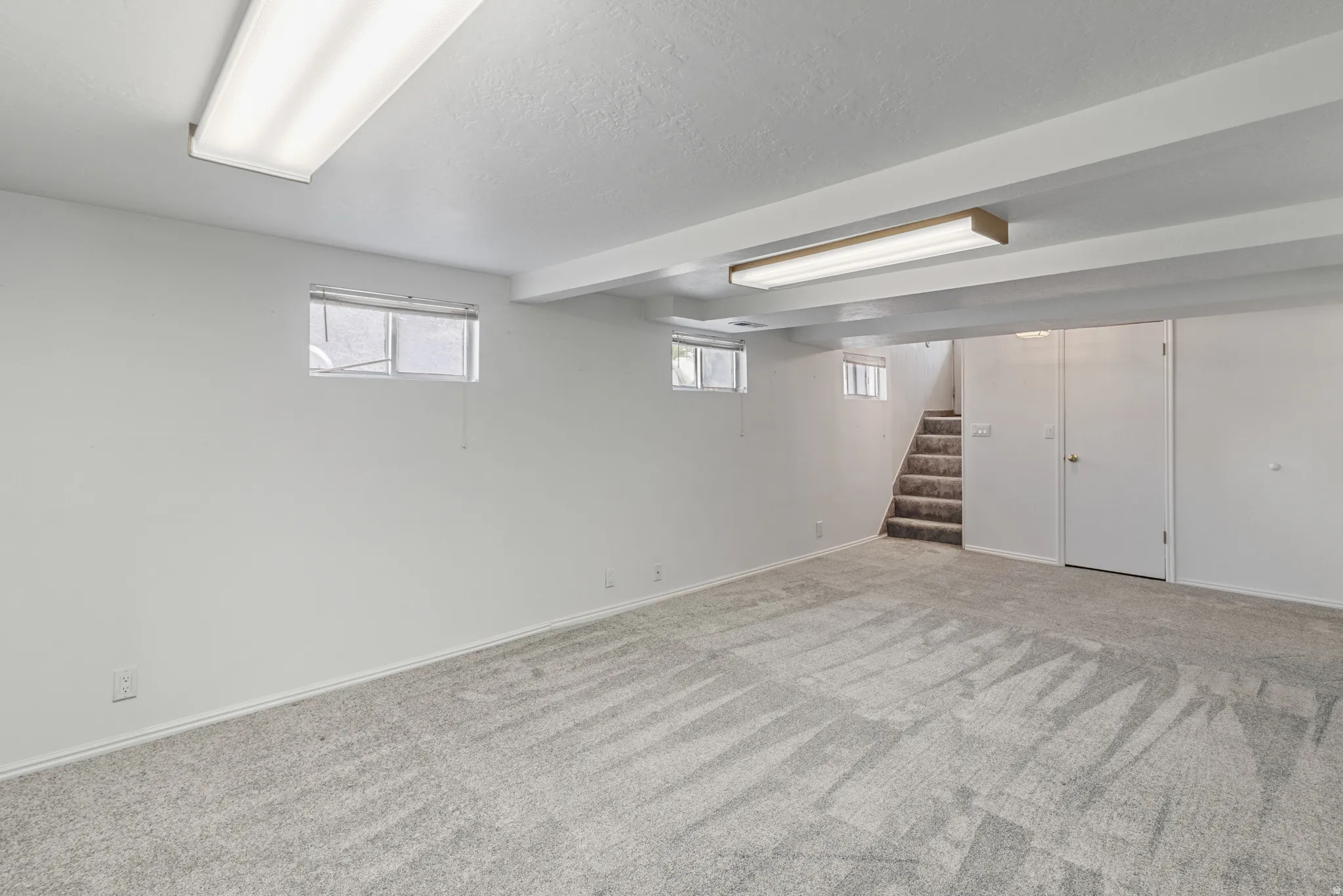 Below grade area with carpet floors and a textured ceiling
