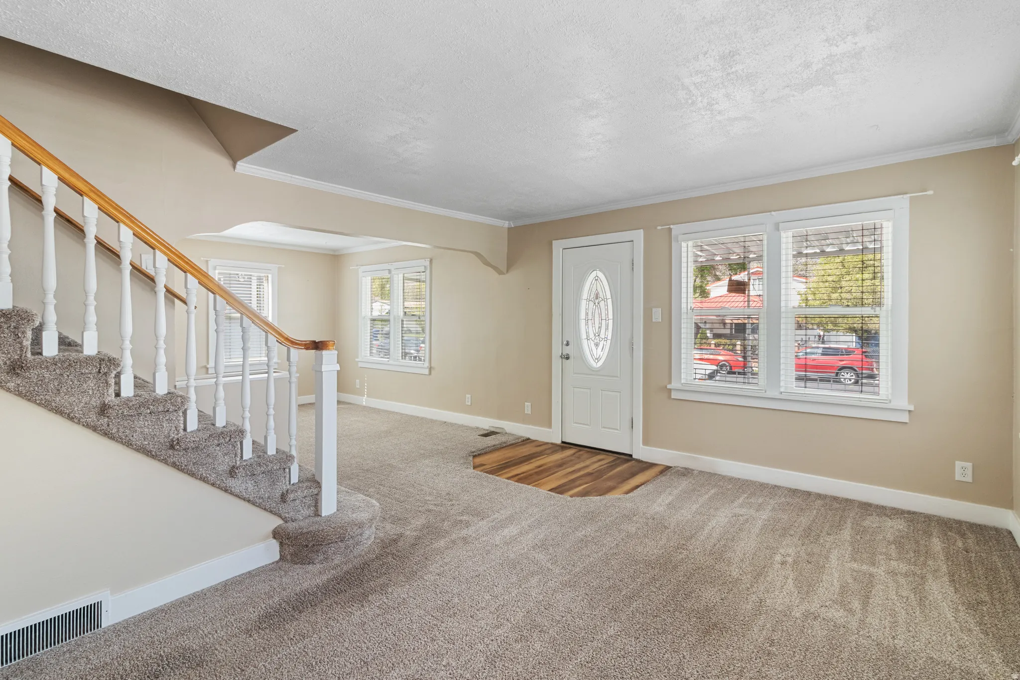 Carpeted foyer with a textured ceiling and crown molding