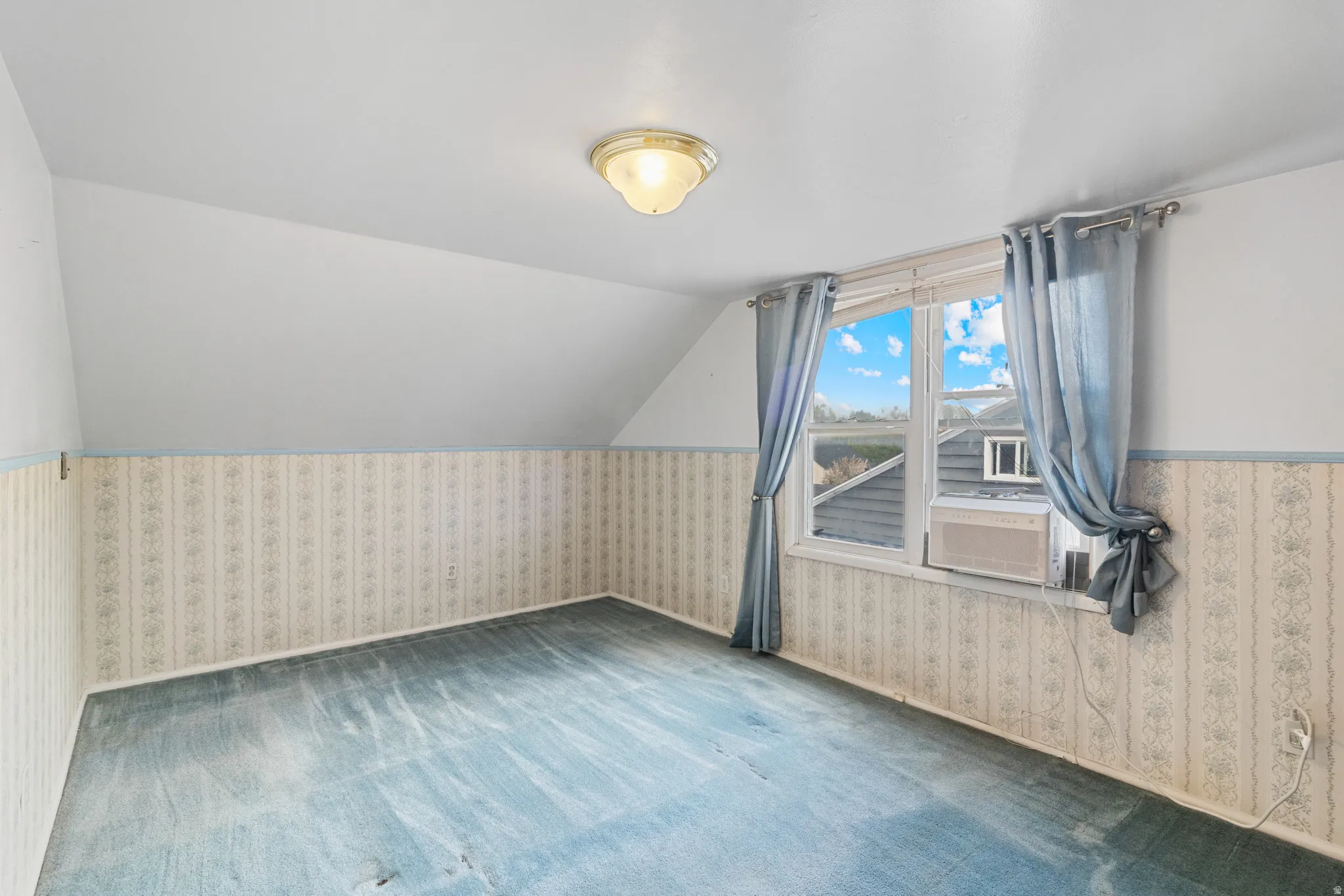 Additional living space with lofted ceiling, wallpapered walls, a wainscoted wall, and carpet flooring