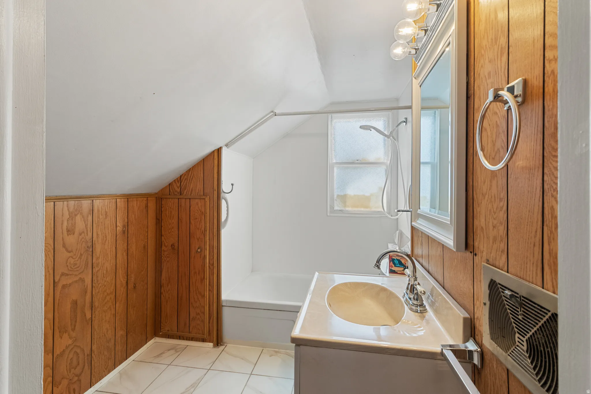 Full bathroom featuring wood walls, vanity, vaulted ceiling, and bathing tub / shower combination
