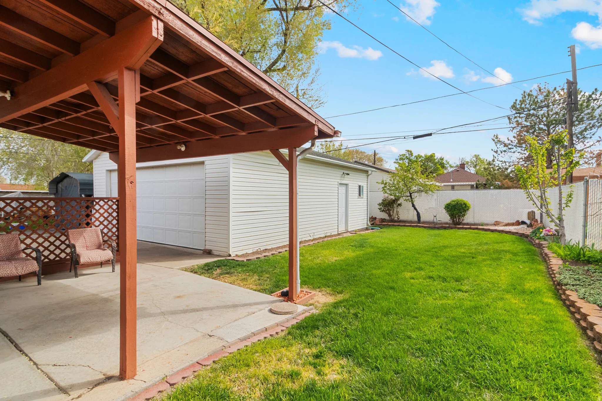 Fenced backyard with an outdoor structure, a garage, and a patio area