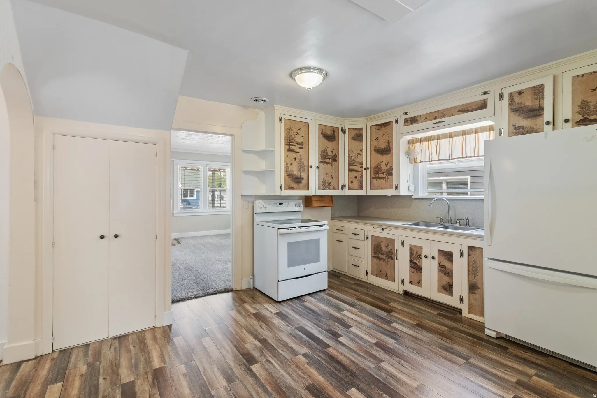 Kitchen with white appliances, open shelves, light countertops, and cream cabinets