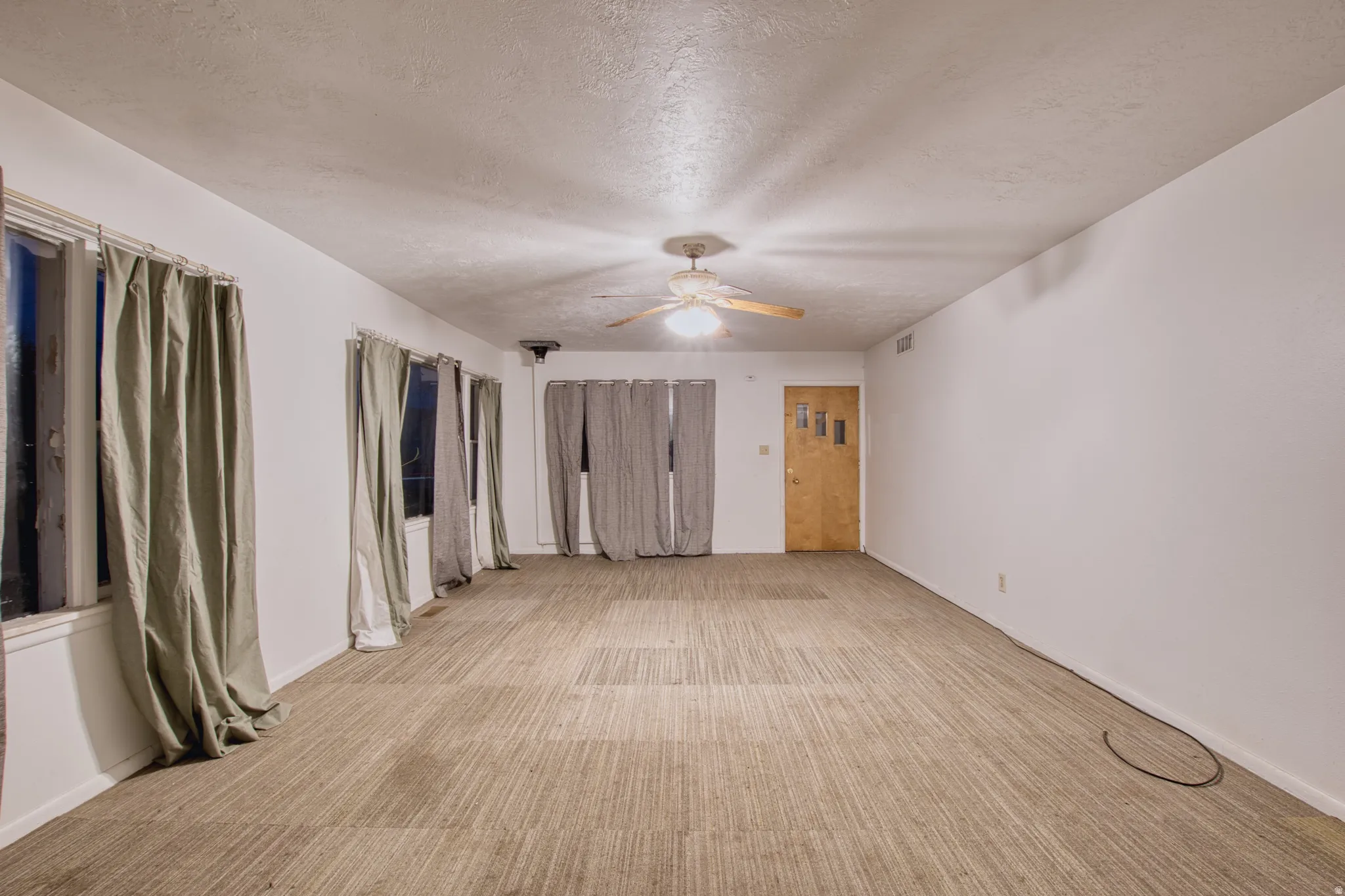 Unfurnished bedroom with light carpet, a textured ceiling, a ceiling fan, and a closet
