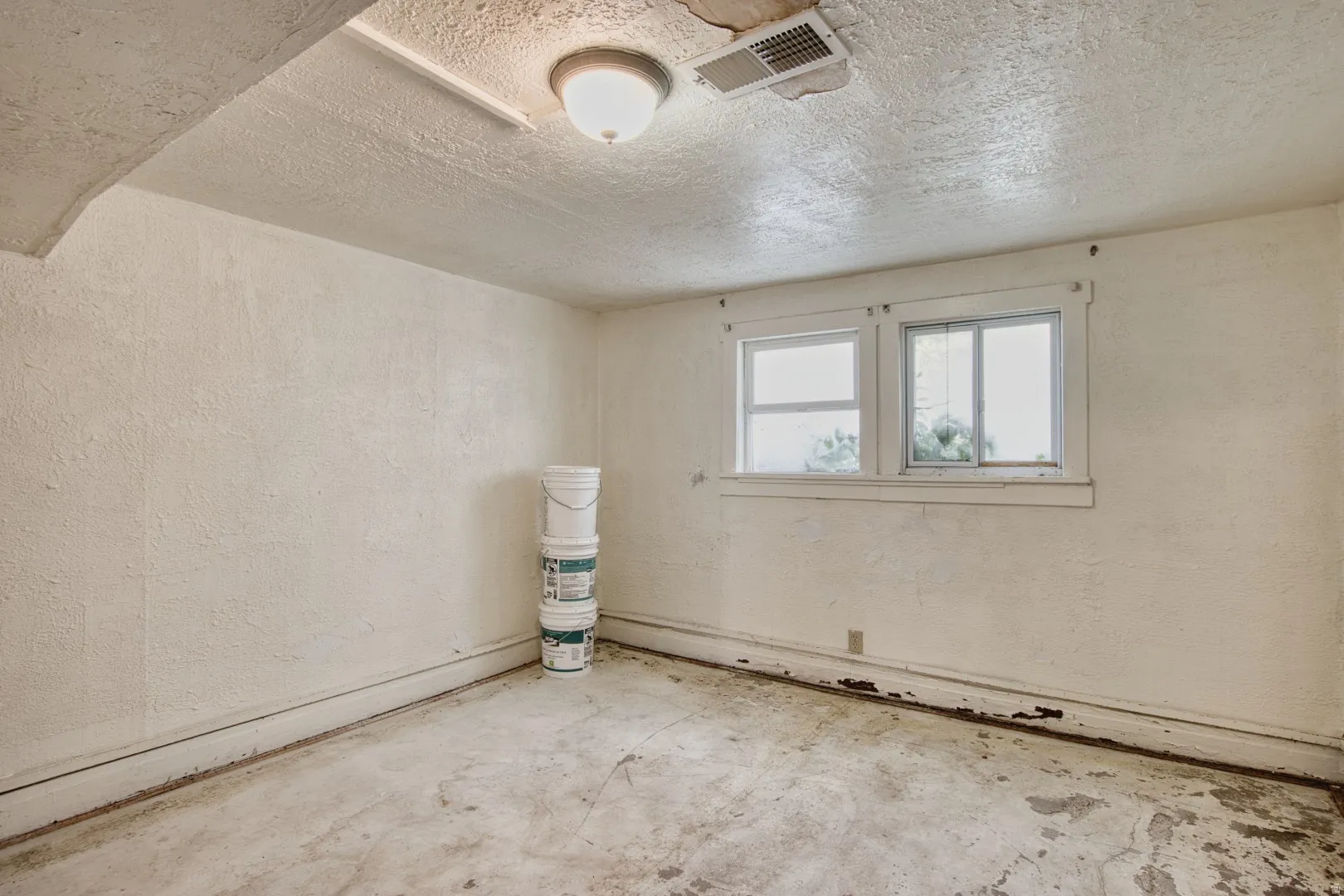 Empty room featuring concrete floors, a textured ceiling, and a textured wall