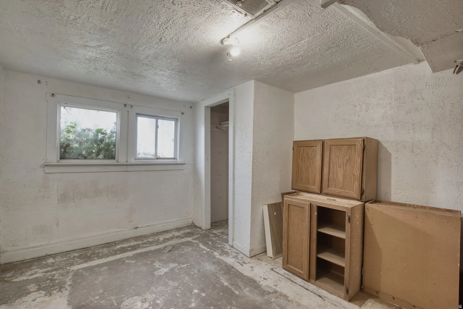 Unfurnished bedroom featuring a textured wall, a textured ceiling, and a closet