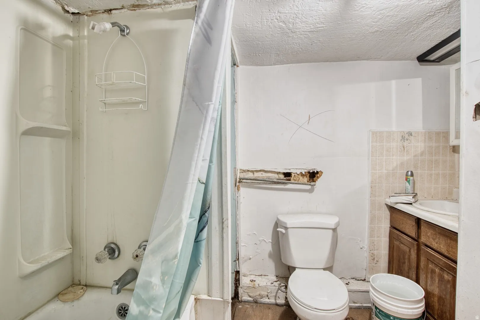 Full bathroom featuring vanity, shower / tub combo, and a textured ceiling