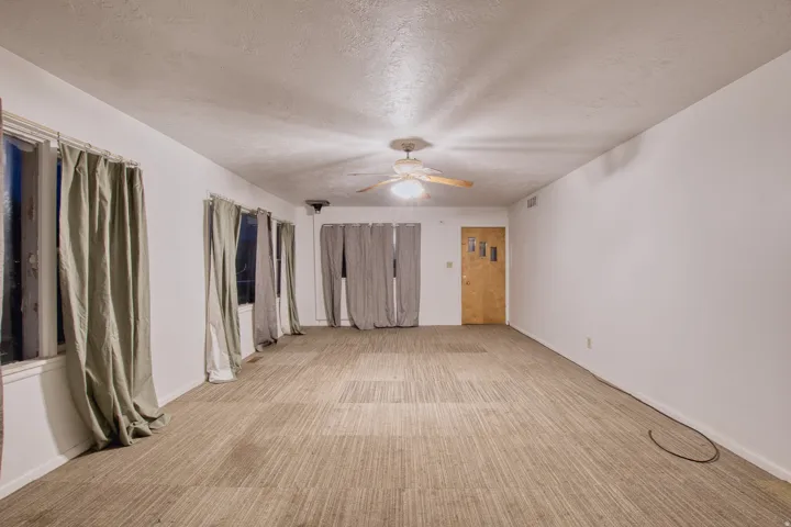 Unfurnished bedroom with light carpet, a textured ceiling, a ceiling fan, and a closet