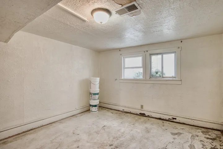 Empty room featuring concrete floors, a textured ceiling, and a textured wall