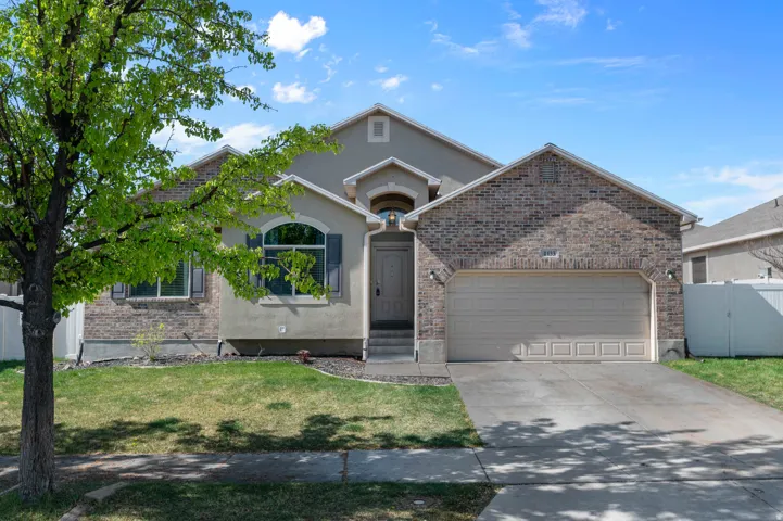 Single story home featuring a garage, driveway, stucco siding, and a gate