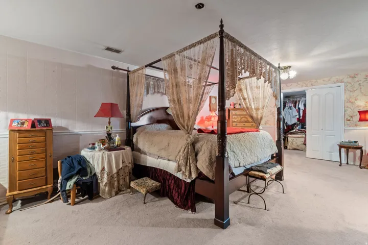 Bedroom featuring wallpapered walls, light carpet, and a closet