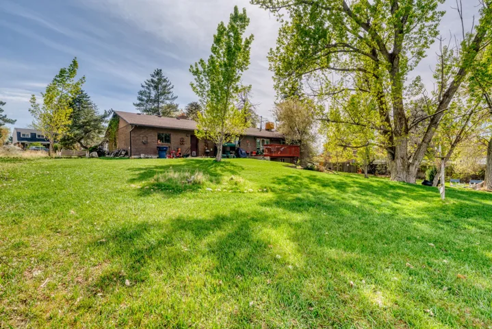 Back of house with brick siding, a yard, and a wooden deck