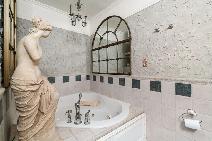 Full bathroom featuring a tub with jets, crown molding, wainscoting, a textured wall, and tile walls