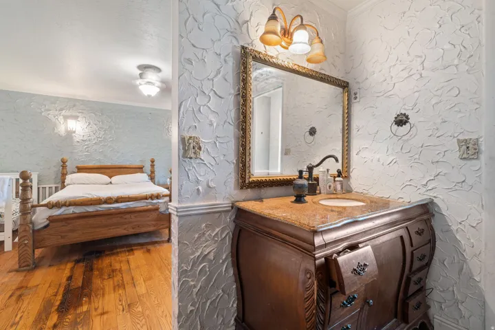 Ensuite bathroom with ornamental molding, vanity, and hardwood / wood-style flooring
