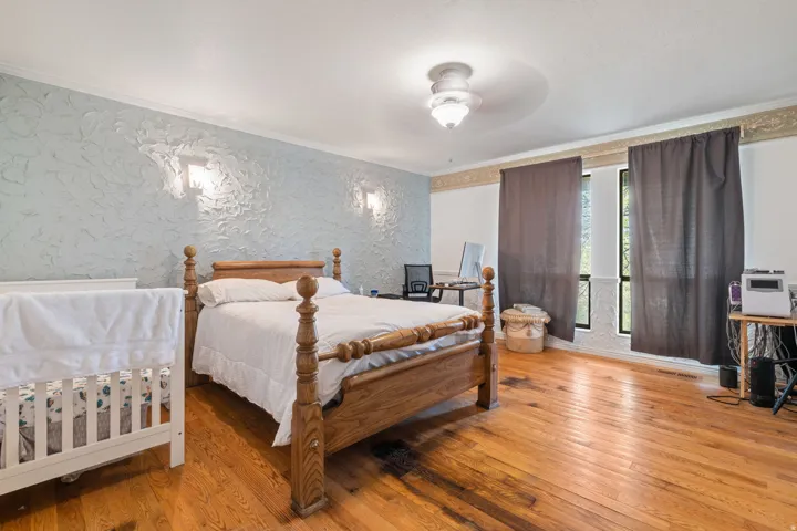 Bedroom featuring hardwood / wood-style floors, crown molding, ceiling fan, and wallpapered walls