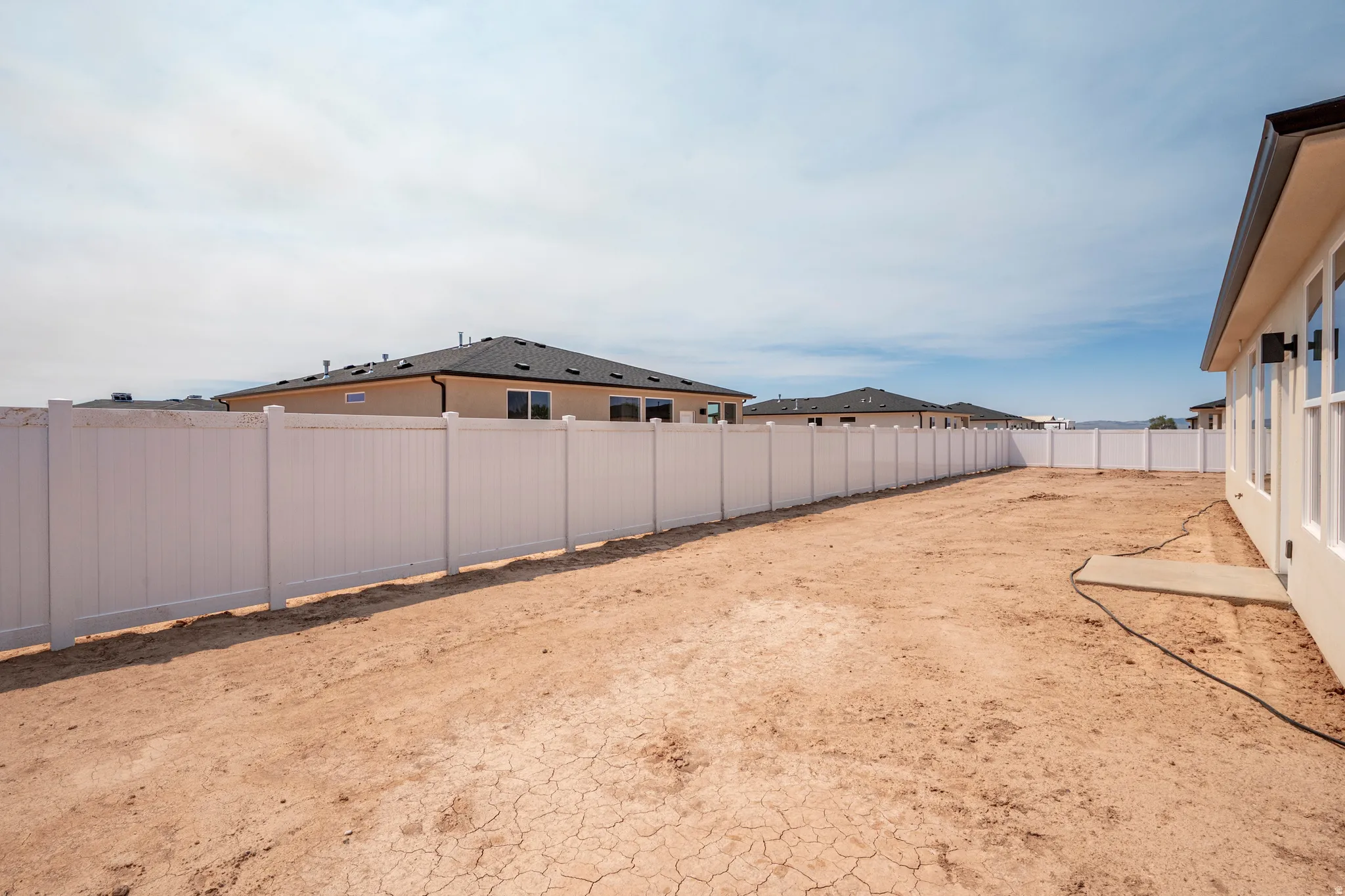 Expansive rear yard featuring a privacy fence, an exterior concrete pad, and stucco siding