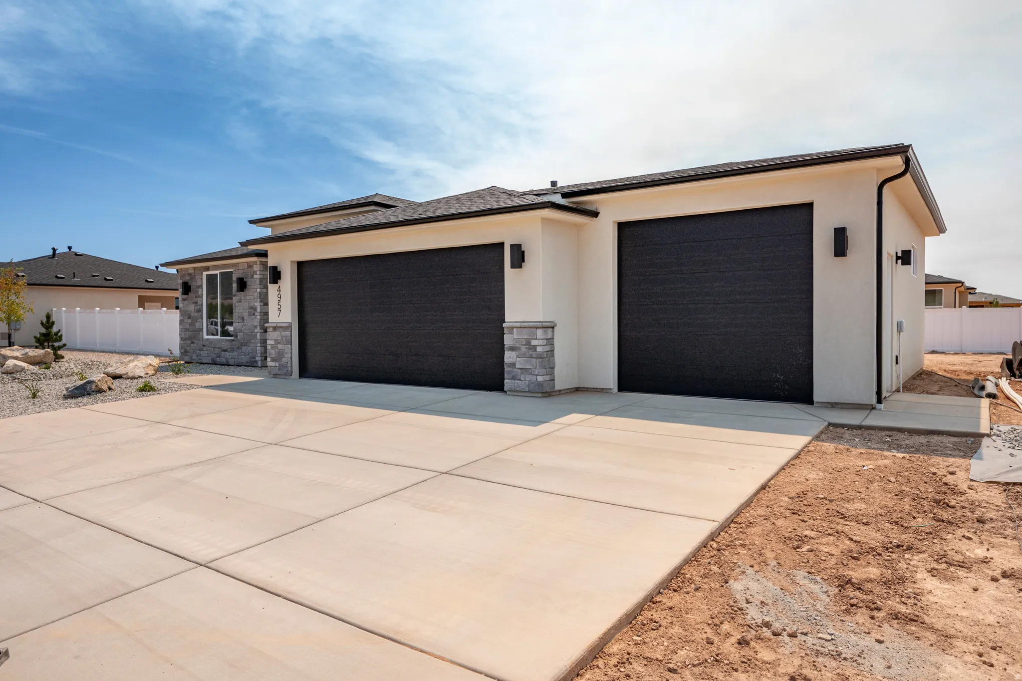 Contemporary single-story residence featuring a dual black garage door entry