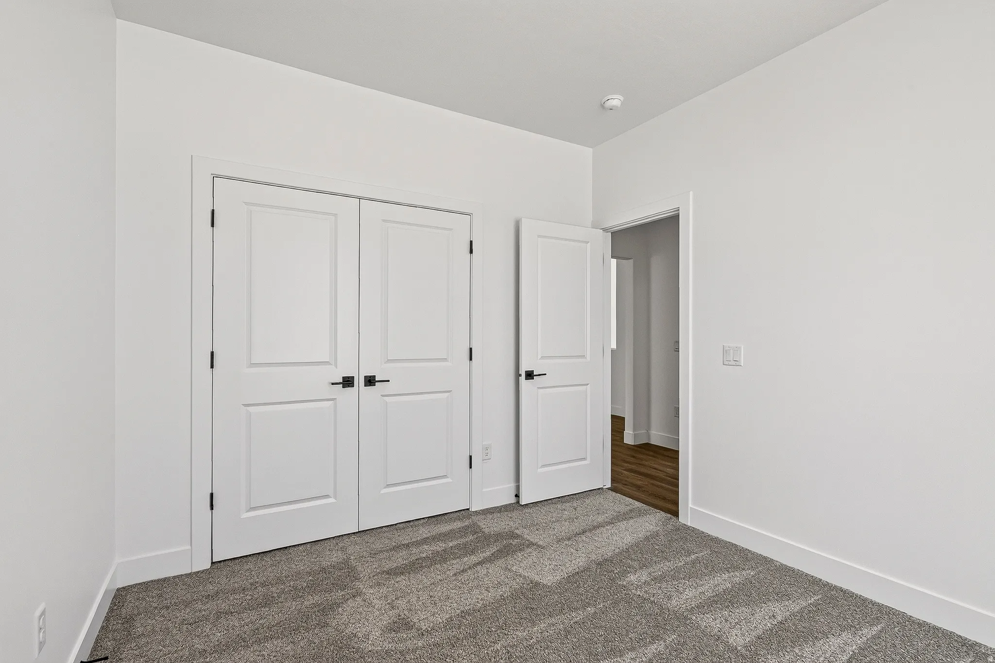 White interior with light gray carpet flooring, white baseboards, and white walls