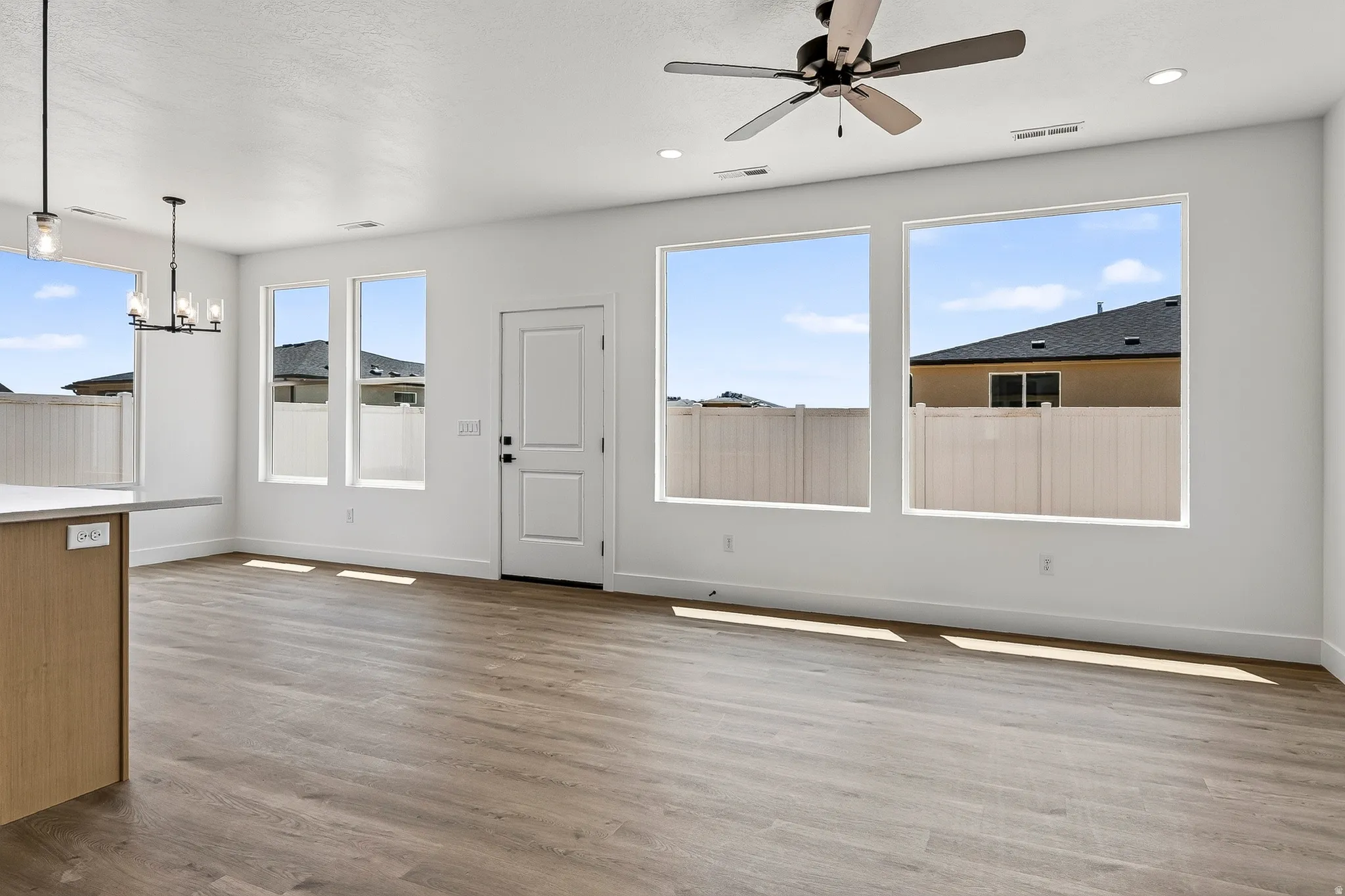 Bright interior space featuring wood-finish flooring, a contemporary ceiling fan, recessed lighting, and multiple large windows