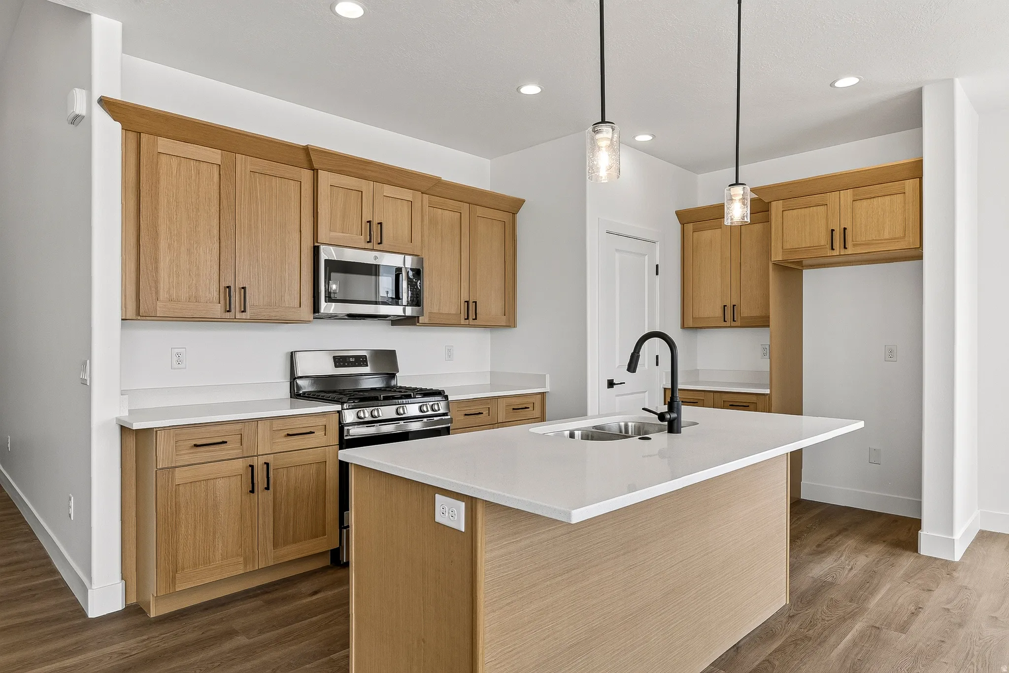 Open-concept kitchen featuring an expansive center island with an undermount sink and matte black faucet