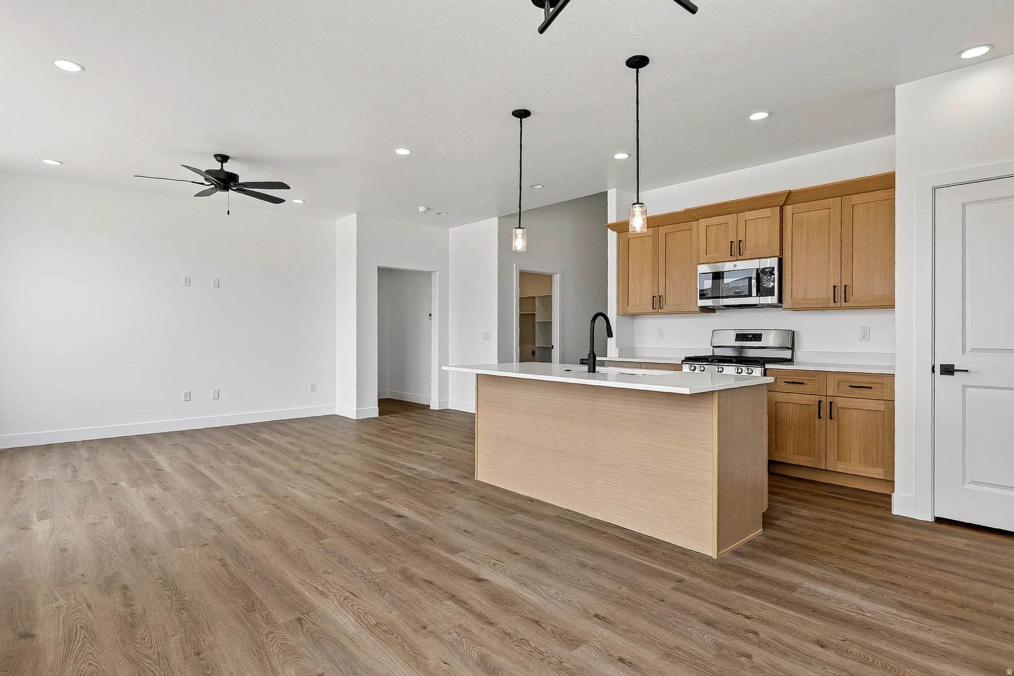 Open-concept living space featuring wood-finish flooring, recessed lighting, and a black ceiling fan