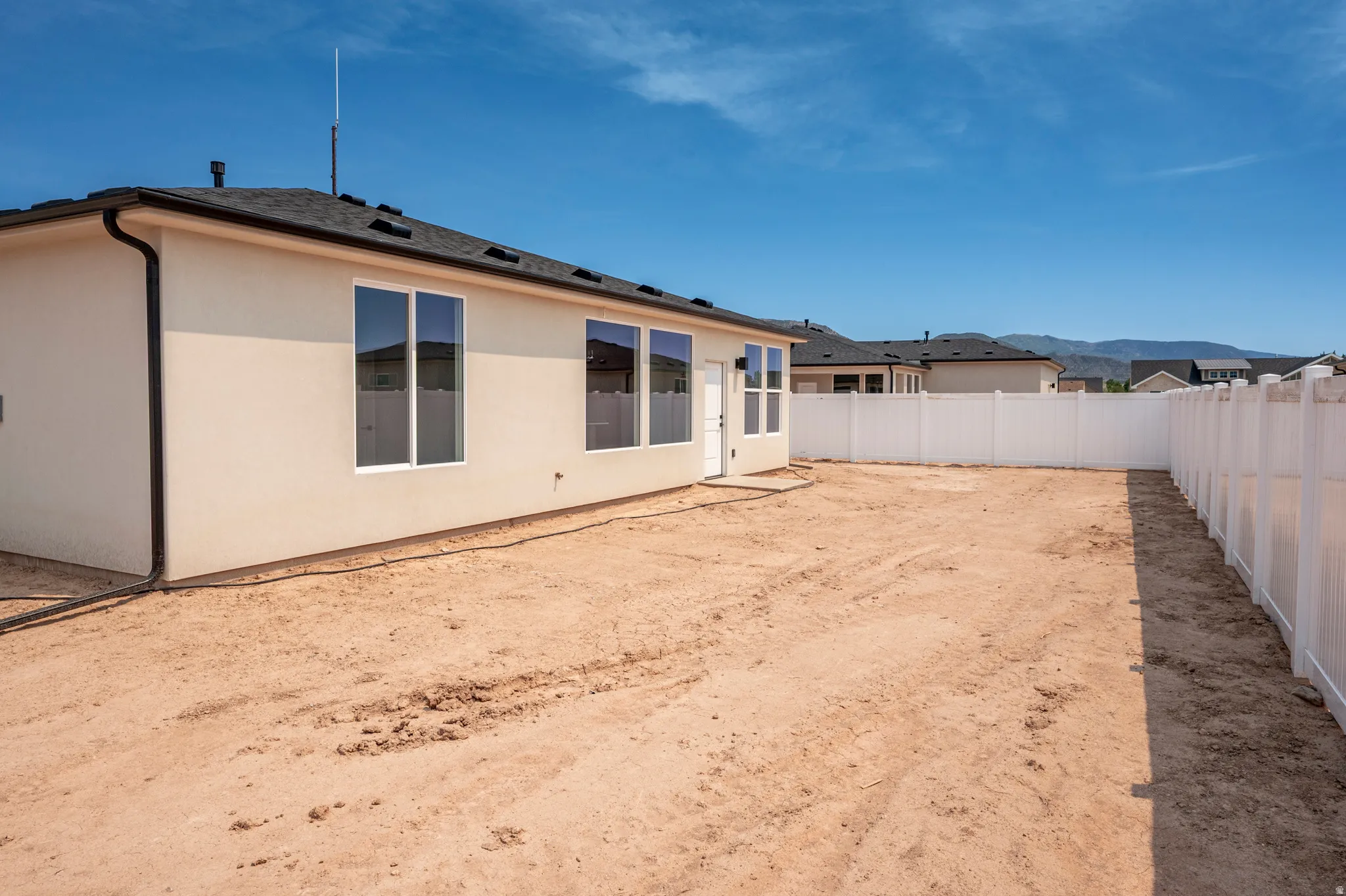 Spacious backyard with a durable vinyl privacy fence and a rear patio door