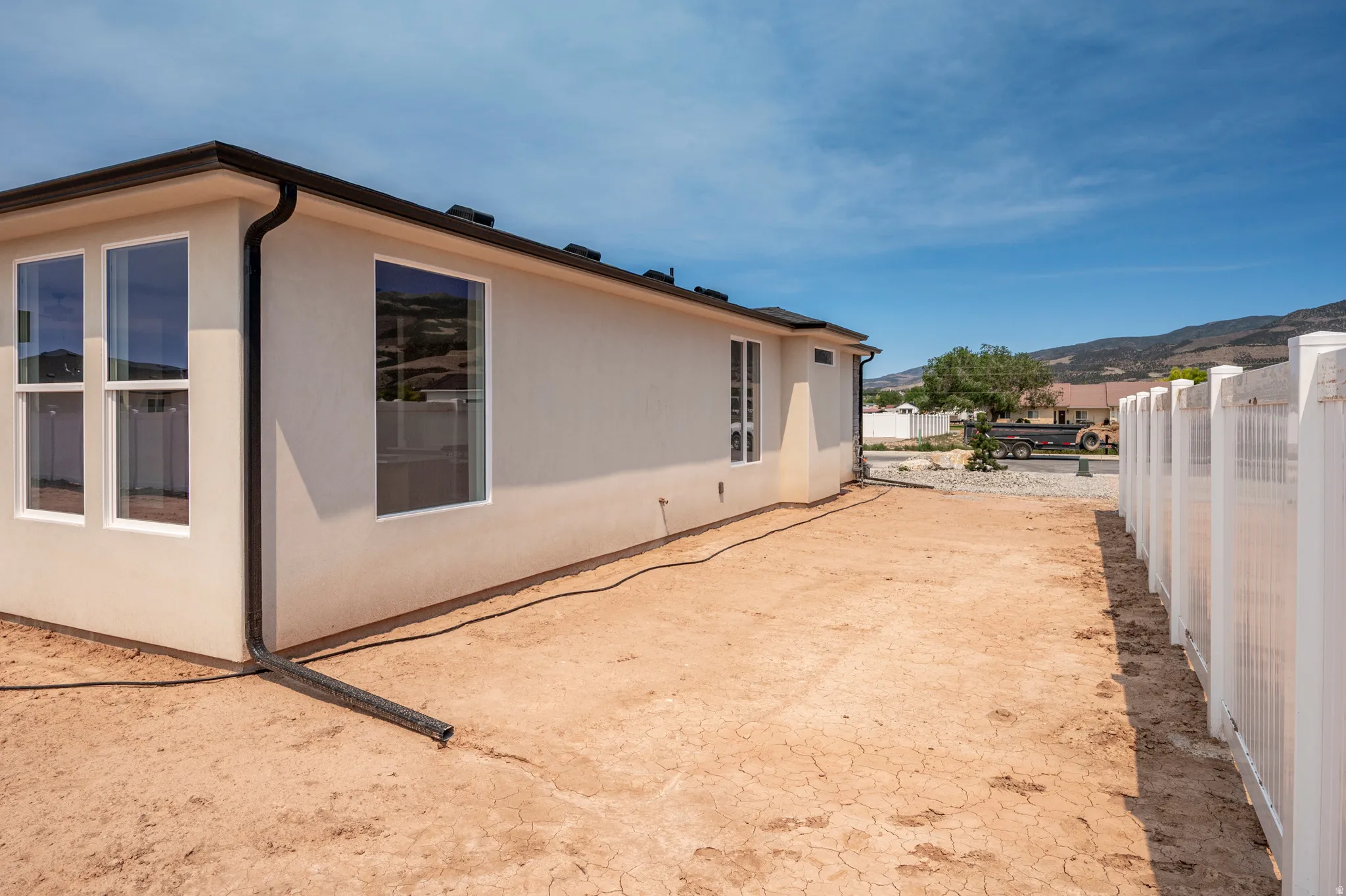 Exterior stucco siding with multiple windows and a black gutter system