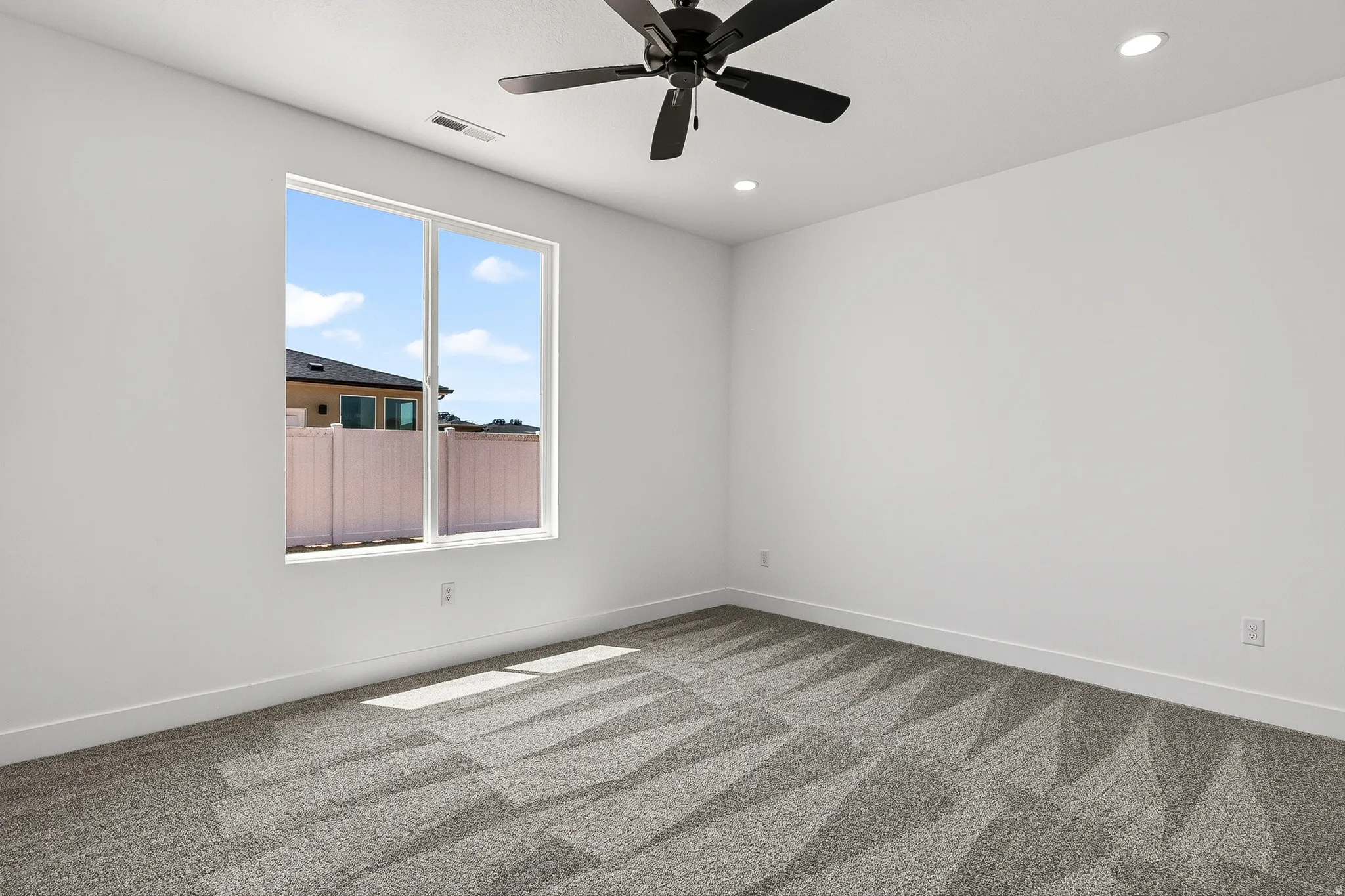 Recessed lighting illuminates this room featuring white walls and a geometric patterned carpet