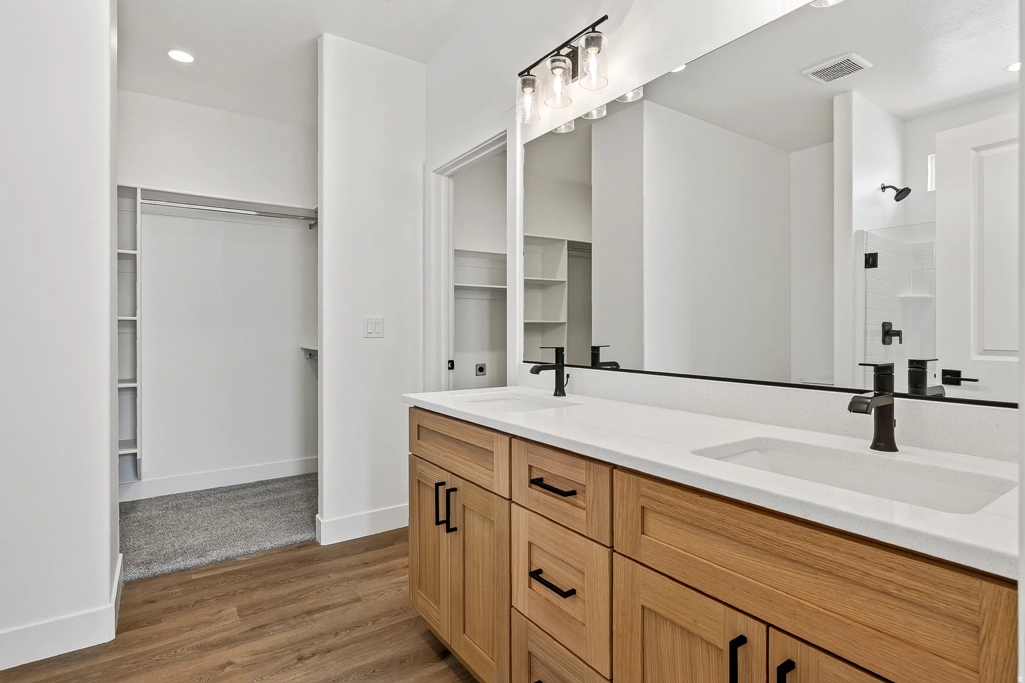 Double vanity with light wood-finish cabinetry and matte black hardware