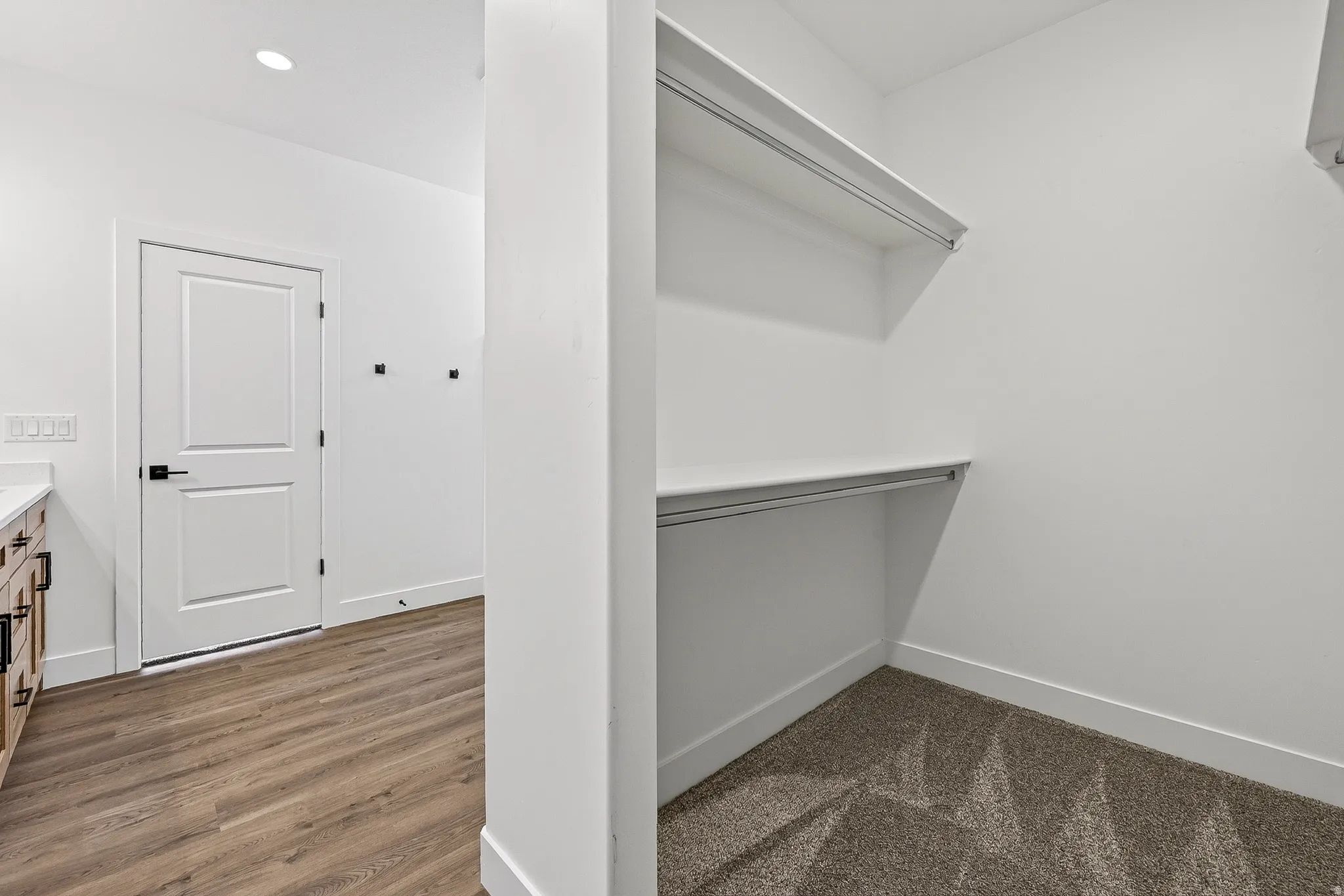Walk-in closet with shelves and hanging rods, featuring gray carpet flooring