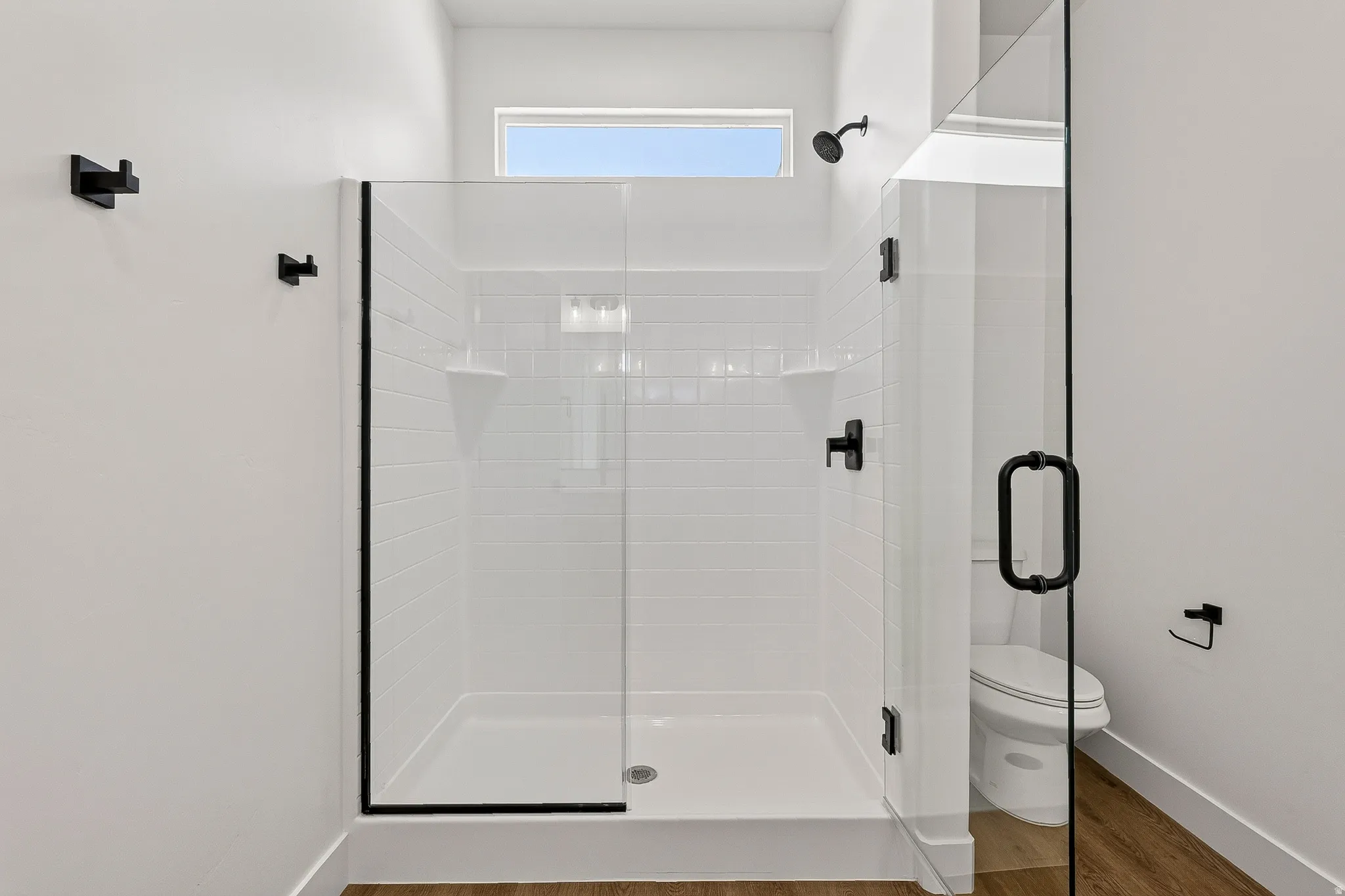 Bathroom featuring a glass-enclosed shower with white subway tile, black fixtures, and a transom window