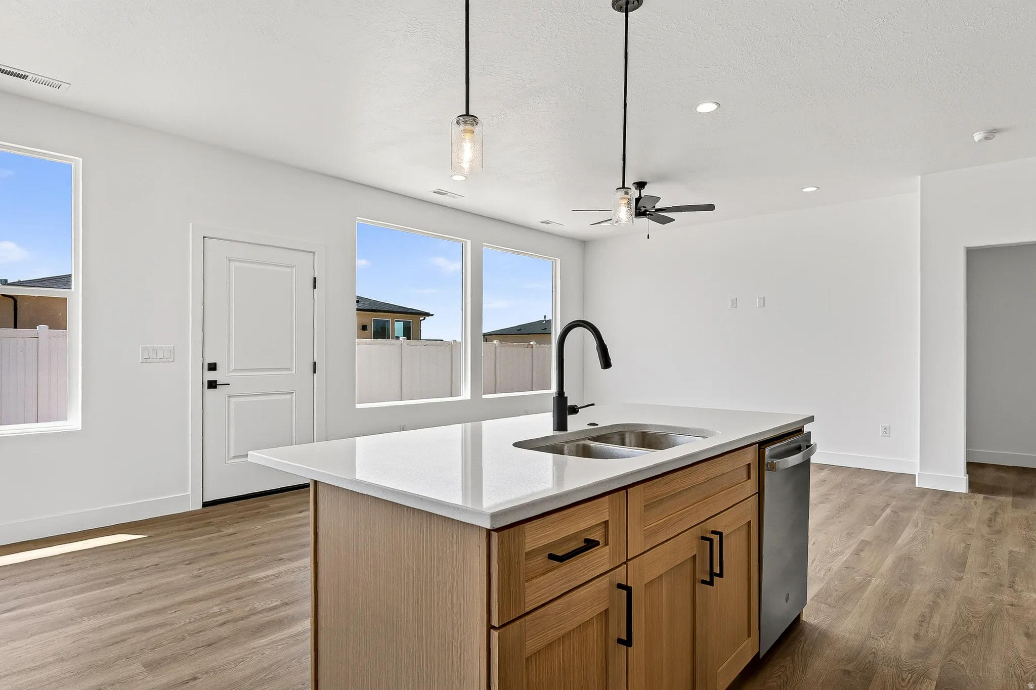 Central kitchen island with a double basin sink, quartz countertop, and a matte black faucet