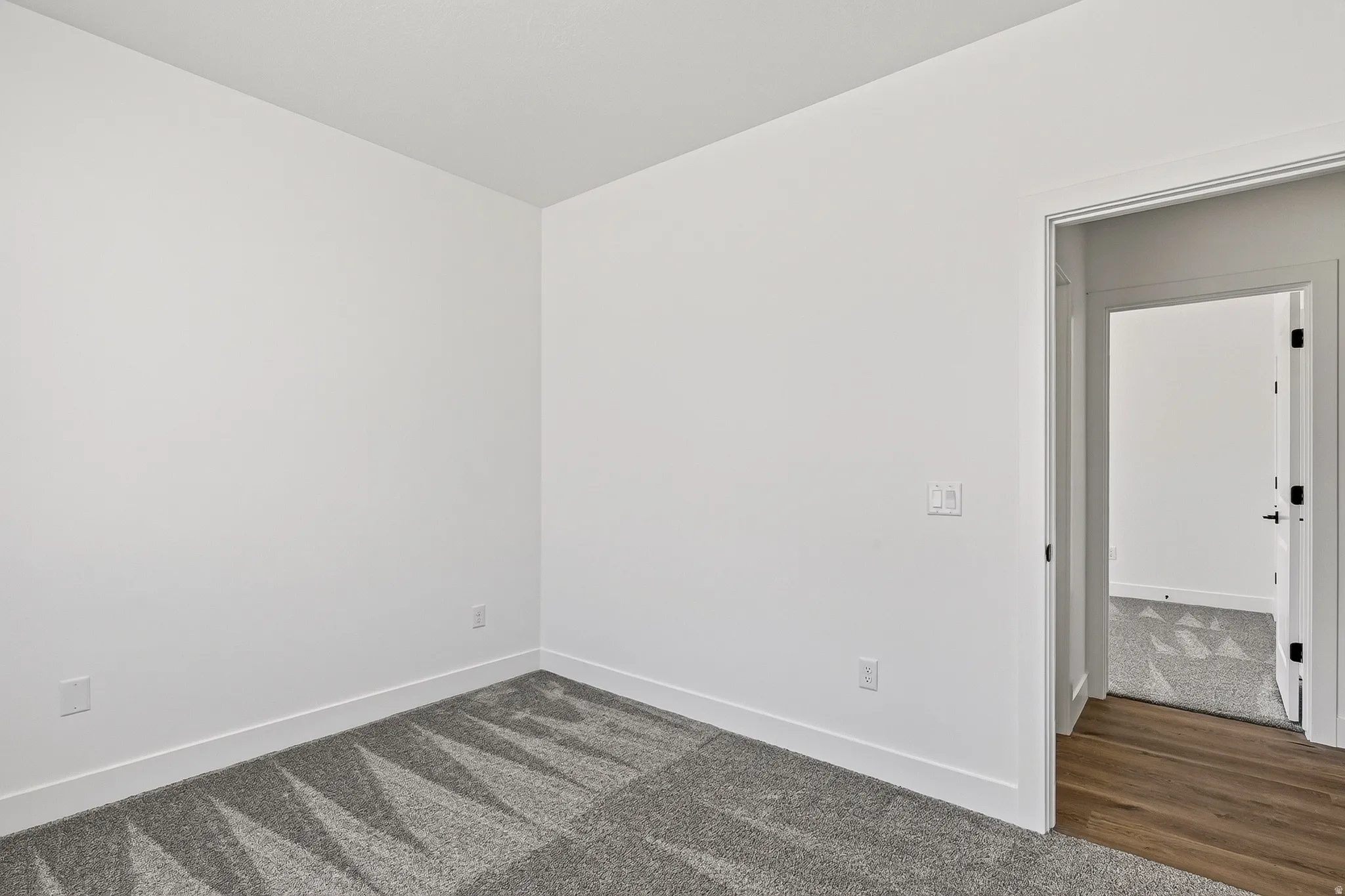 Room featuring light gray patterned carpet and white walls