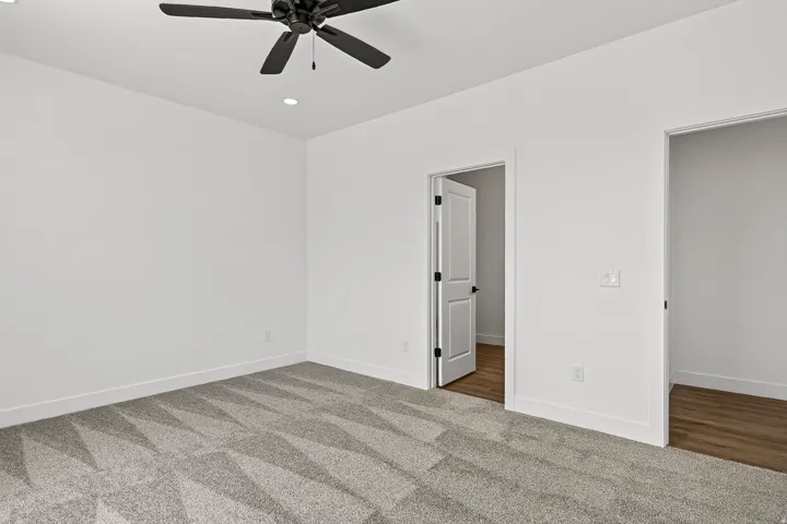 Room featuring patterned carpet flooring, recessed lighting, and a ceiling fan with matte black blades