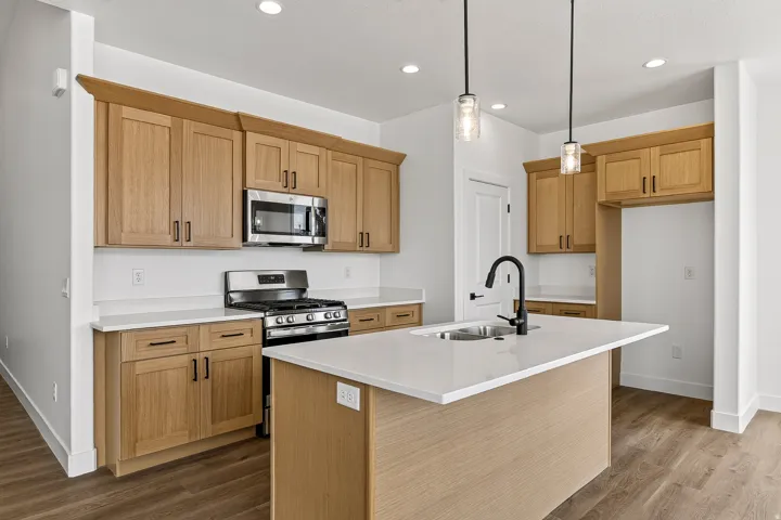 Open-concept kitchen featuring an expansive center island with an undermount sink and matte black faucet
