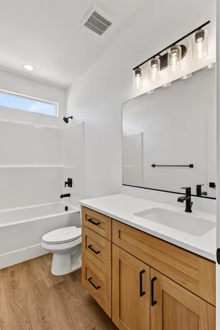 Bathroom featuring a light wood-finish vanity with black hardware, a white countertop with an integrated sink, and black fixtures