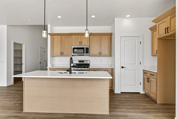 Modern kitchen featuring light wood cabinetry, a central island with a white countertop, and wood-finish flooring