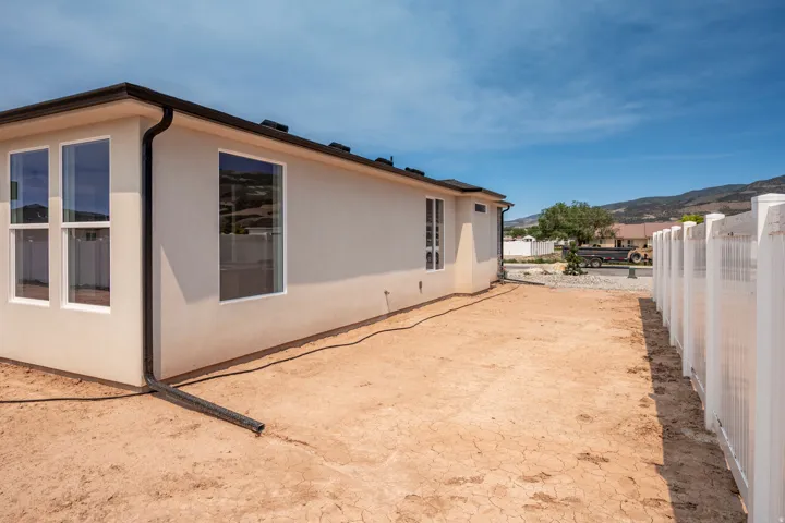 Exterior stucco siding with multiple windows and a black gutter system